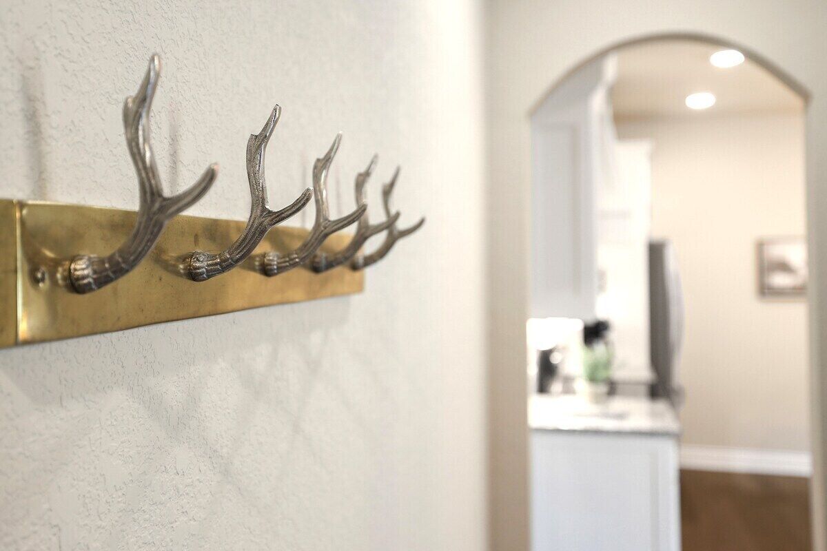 A wall-mounted metal rack with antler-shaped hooks.