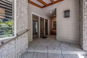 A hallway with a terrazzo floor, a bench, and a door leading to another room.