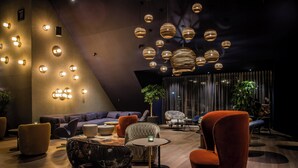 A modern lounge area with multiple seating options, including sofas and chairs, a small round table, and a potted plant.