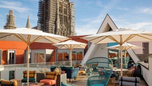 A rooftop terrace with outdoor seating, umbrellas, and a view of a tall building under construction.