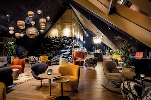 Um interior moderno com teto inclinado, várias áreas de estar e um bar com vista para a cidade.