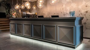 A reception area with a modern counter, multiple light fixtures, and a patterned wall.