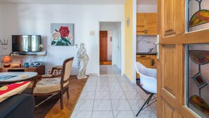 A living room with a TV, a statue, a dining area with a table and chairs, and a kitchen with wooden cabinets. - MARIC 1 apt for 4+2, only 40 m from the beach in Mastrinka (Mastrinka)