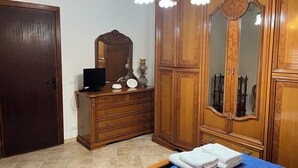 Ein Schlafzimmer mit einem hölzernen Schminktisch, einem Fernseher, einem Spiegel und einem Bett mit Handtüchern.