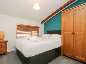 A bedroom with a bed, wooden wardrobe, and a window with blinds. - 11 Towan Valley (Truro)