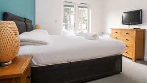 Ein Schlafzimmer mit Bett, Fernseher, Kommode und Fenster.