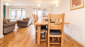 Ein großzügiger Wohnbereich mit Esstisch aus Holz, mehreren Stühlen, einer Couch und einem Balkon mit Aussicht.