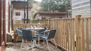 Eine Holzterrasse mit einem runden Tisch und vier Stühlen, umgeben von einem Holzzaun.