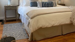 A neatly arranged bedroom with a large bed, two bedside tables, a ceiling fan, and a window with blinds.