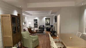 A spacious living room with a wooden dining table, green armchairs, and a sofa.
