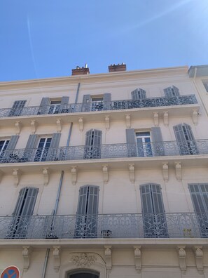 Ein mehrstöckiges Gebäude mit Balkonen, verzierten Geländern und blauem Himmel.