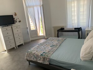 Ein Schlafzimmer mit Bett, Kommode, Fernseher und Heizkörper.