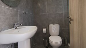 A bathroom with a white sink, a toilet, and a trash can. - Phaedrus Living Seaside Luxury Flat Athina 118 (Paphos)