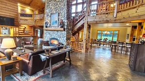 A spacious log cabin interior with a fireplace, a dining area, and a balcony. - River Ridge Lodge: Luxury Lodge on the Menominee River (Stephenson)