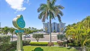Schild für das Crystal Palm Beach Resort mit freiem Blick auf die umliegende Bepflanzung und einem mehrstöckigen Gebäude im Hintergrund.