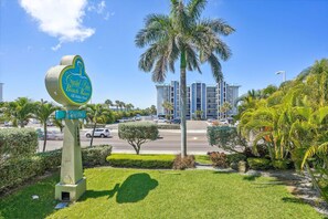 Une enseigne indiquant l’emplacement du Crystal Palm Beach Resort, offrant une vue dégagée sur la végétation environnante et un immeuble à plusieurs étages en arrière-plan.