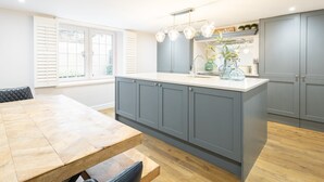 A modern kitchen with grey cabinets, a wooden dining table, and a central island.