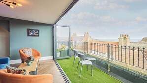 A balcony with a view of the city, furnished with a sofa, chairs, and a table.