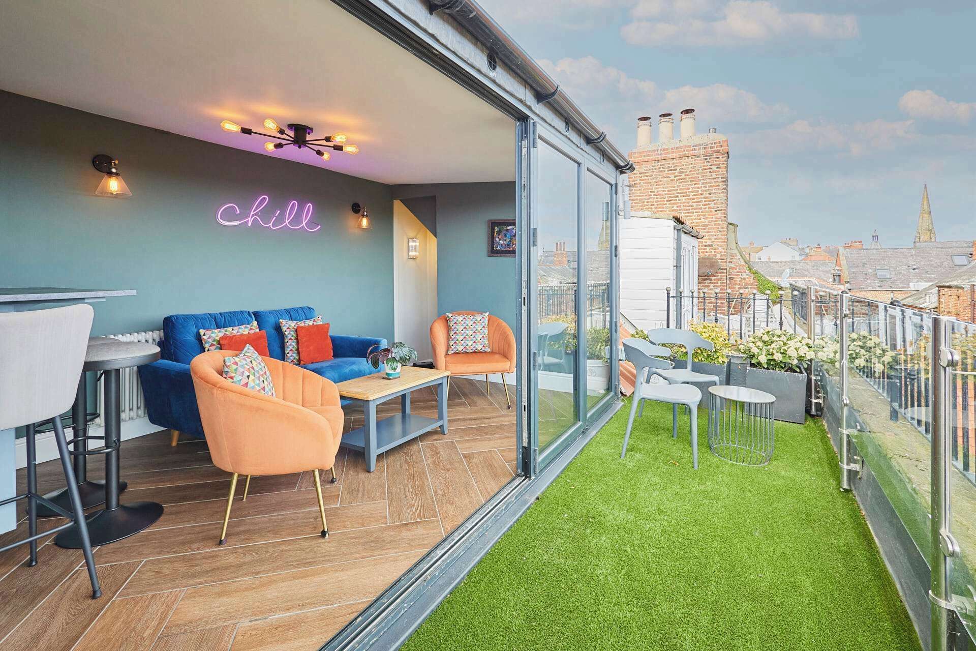 A modern apartment with a balcony, a neon sign, and a city view.