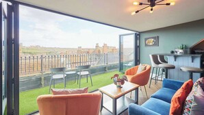 A modern living room with a large sliding glass door leading to a balcony with a city view.