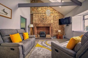 A living room with a stone fireplace, a sofa set, and a television.