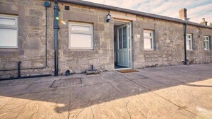 A stone building with a single door and windows, a paved ground, and a clear sky. - Host & Stay | Bluebell Cottage (Belford)