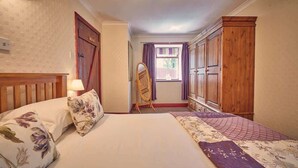 Une chambre à coucher avec un lit, une armoire en bois et une fenêtre avec des rideaux.