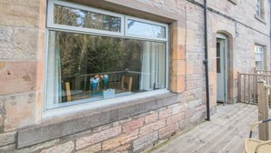 Ein Steinhaus mit einem großen Fenster mit Blick auf einen Garten.