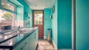 A kitchen with teal walls, a wooden door, and a window.