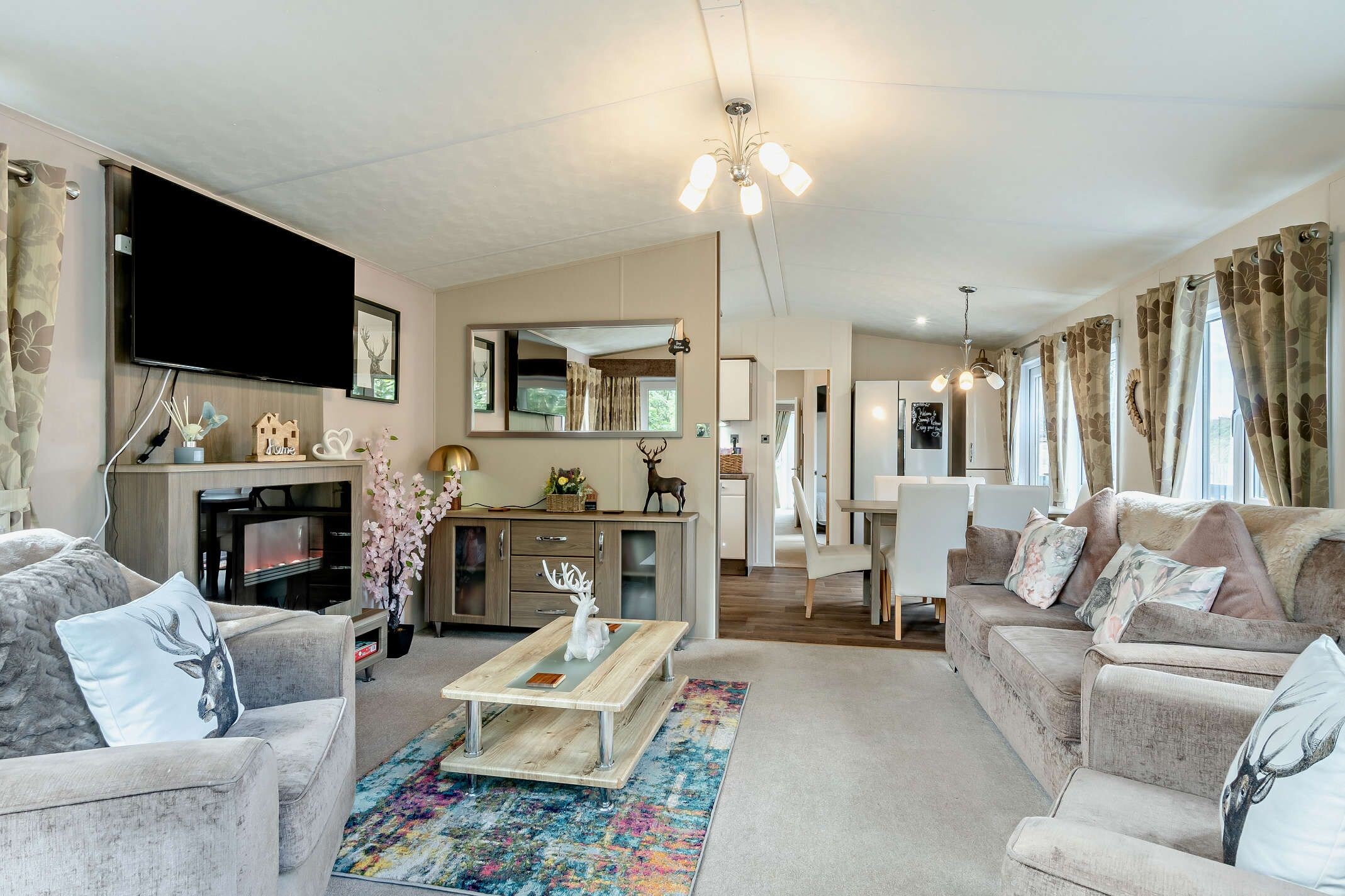 A modern living room with a flat-screen TV, a dining area, and a kitchen.