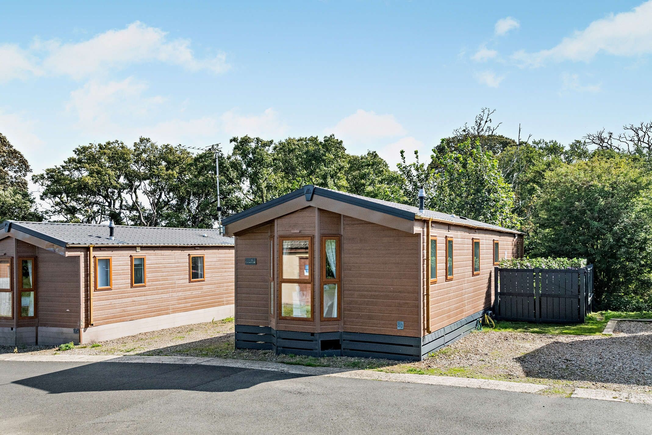 Two small, single-story cabins with a sloped roof, wooden siding, and a fenced yard.