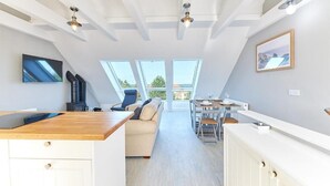 Een moderne keuken met een houten aanrecht, witte kastjes, en een eethoek met een tafel en stoelen.