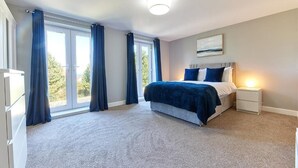 Een slaapkamer met een bed, nachtkastjes, een raam met gordijnen en een plafondlamp.