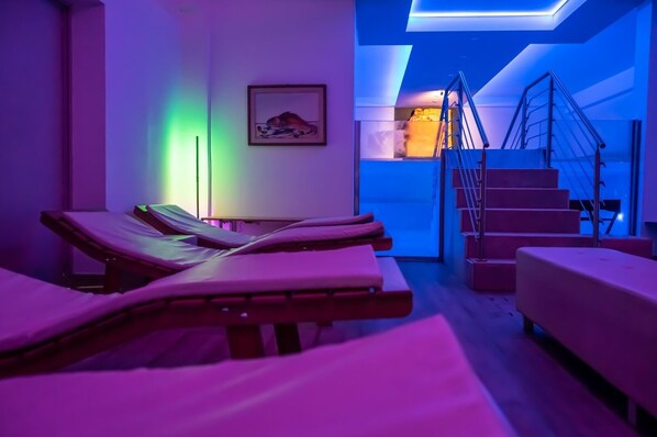 A room with multiple massage tables, a staircase, and a framed picture on the wall.