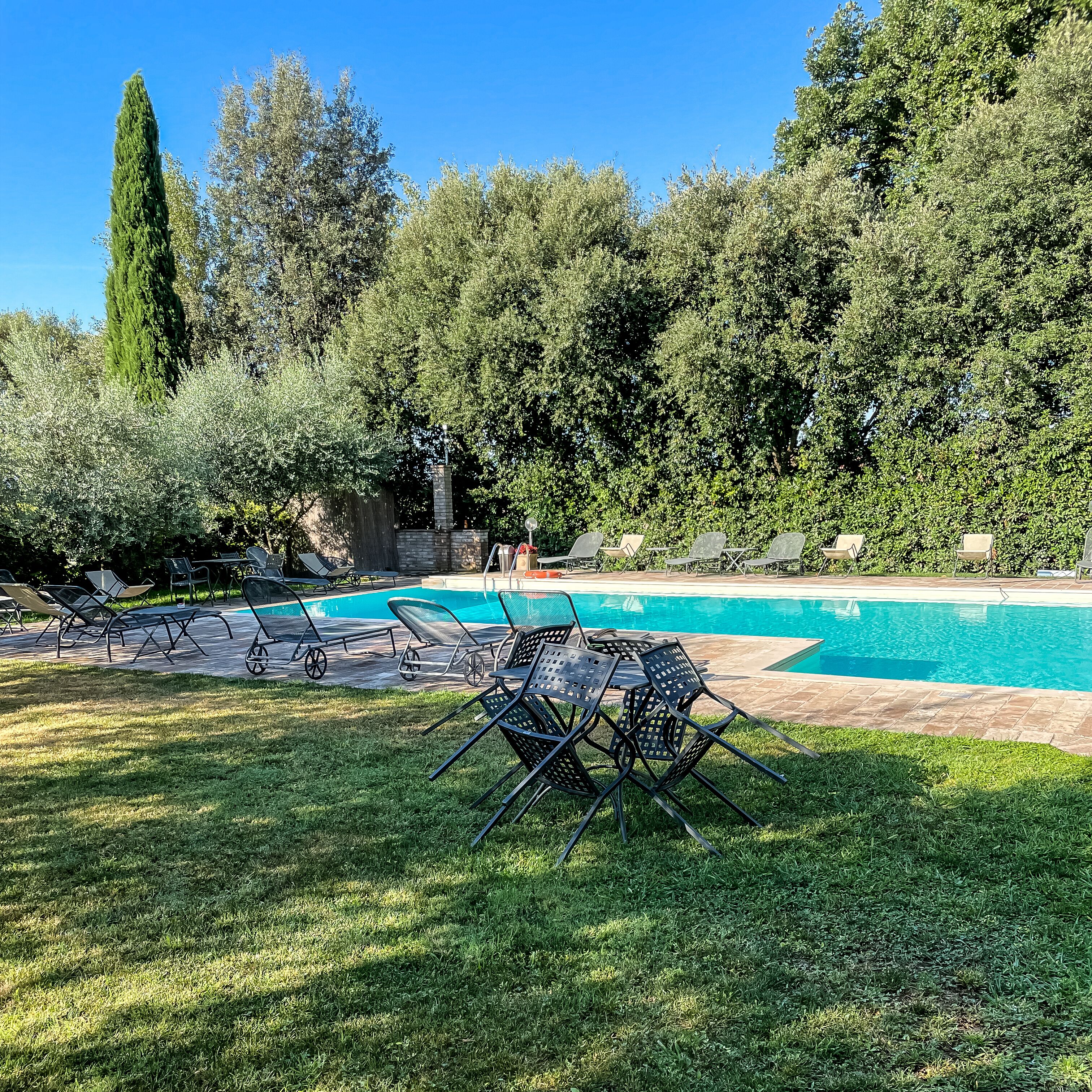 A pool area with lounge chairs and a stone structure.
