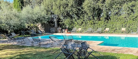 Un área de piscina con sillones de descanso y una estructura de piedra.