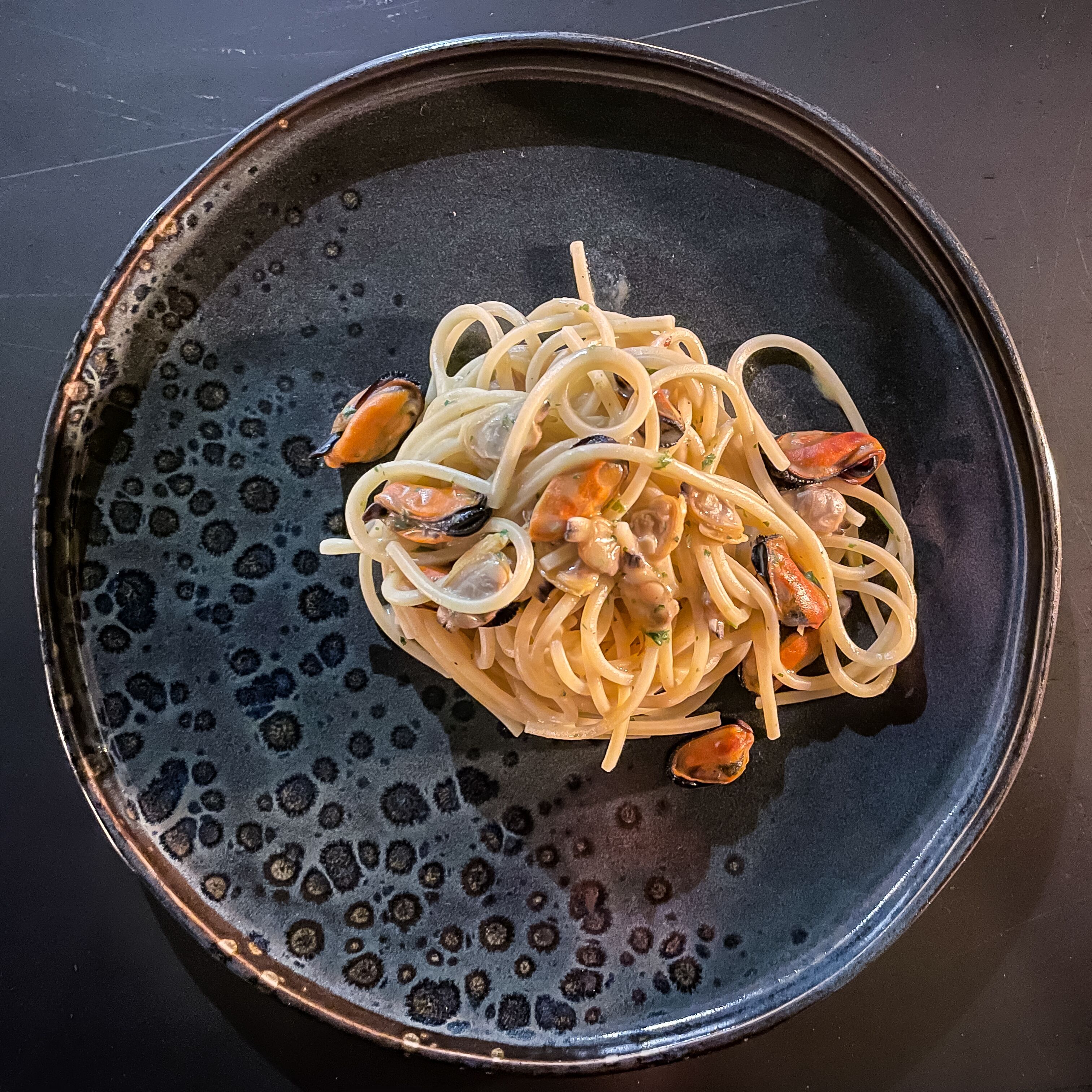 Ein Teller Spaghetti mit Muscheln und Zwiebeln.