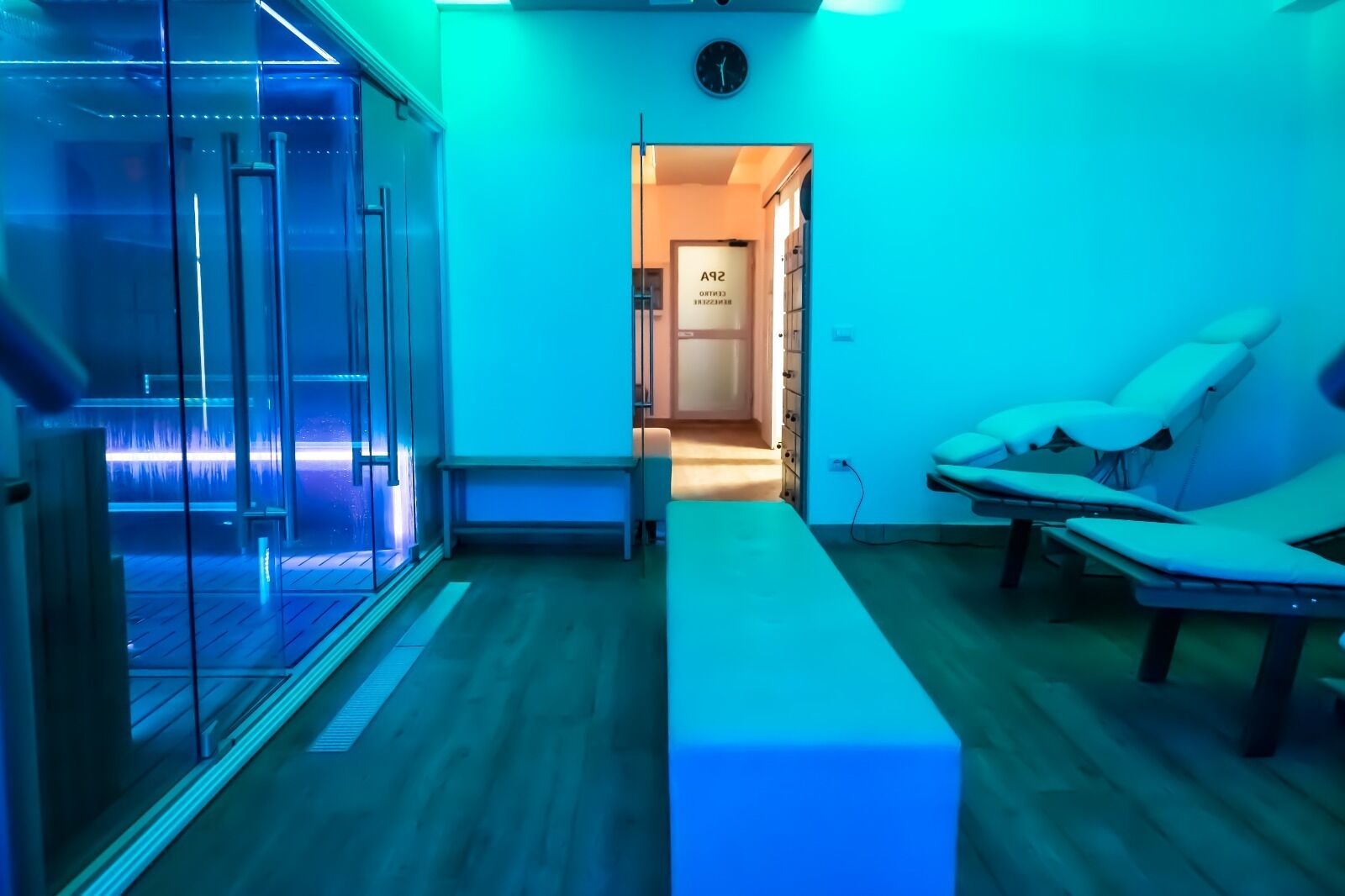 Une salle de spa moderne dotée d’une paroi en verre, d’un banc et de deux chaises longues.