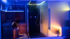 Un baño moderno con cabina de ducha de vidrio, un banco de madera y un perchero para toallas.