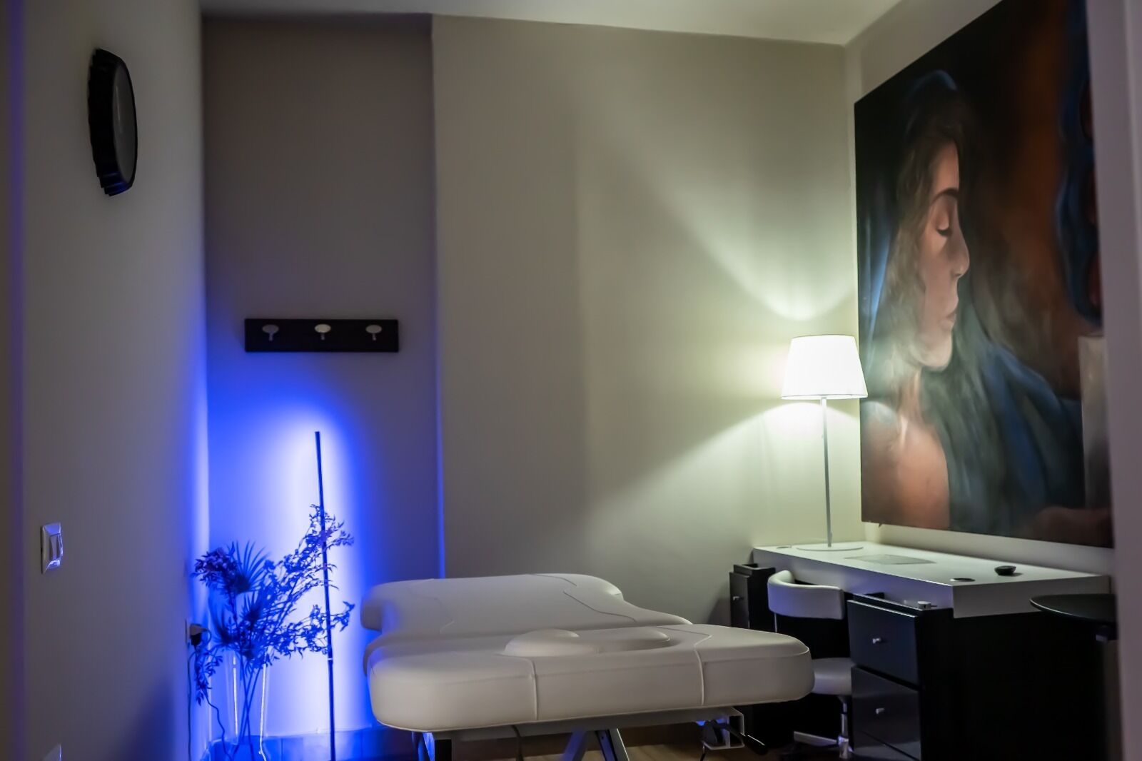 A modern bathroom with a white bathtub, a large mirror, and a blue ambient light.