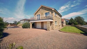 A two-story stone house with a garage, a covered driveway, and a well-maintained lawn. - Host & Stay | Cheviot View (Seahouses)