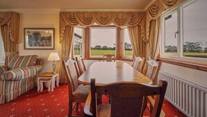 A dining area with a large table and chairs, a sofa, a lamp, and a framed picture on the wall. - Host & Stay | Cheviot View (Seahouses)