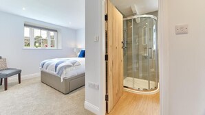 Une chambre à coucher comprenant un lit, un banc, une fenêtre et un espace douche.