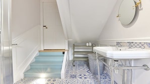 Une salle de bain avec un lavabo blanc, un miroir et un carrelage décoré.