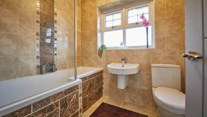Un baño con bañera, lavamanos e inodoro.