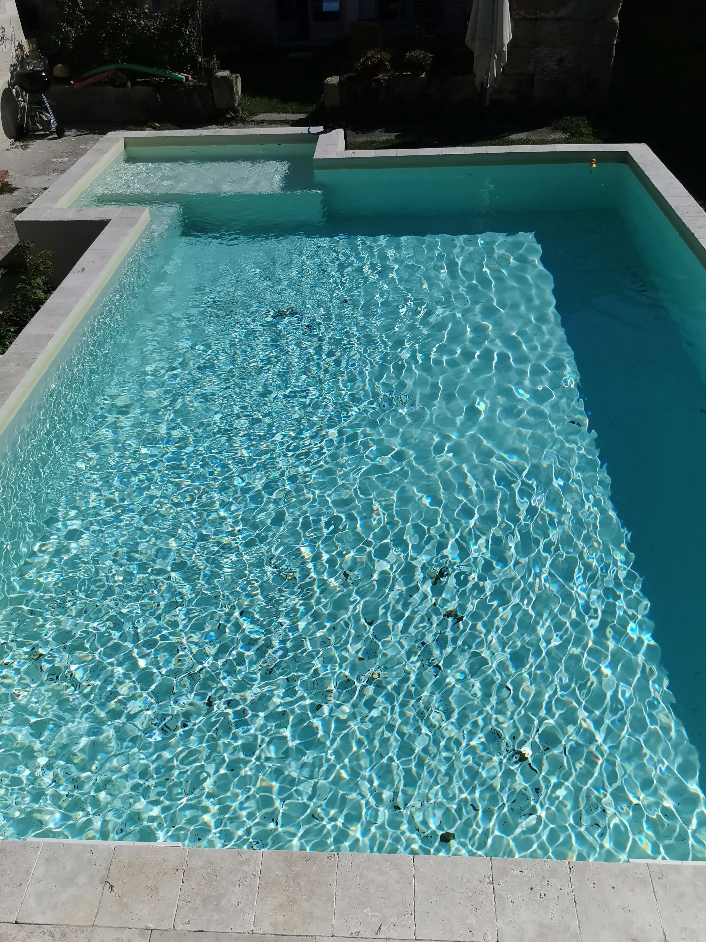 Une piscine rectangulaire à l’eau claire, dont les bords sont recouverts de carreaux.