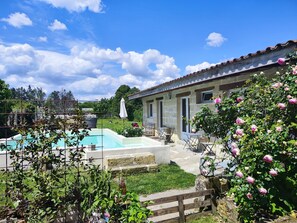A pool area with a stone wall, outdoor seating, and a garden with blooming flowers. - Cottage with a pool, 8 km from St. Emilion (sainte terre)