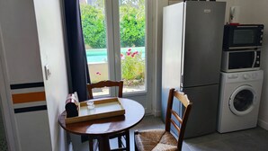 A compact kitchen with a dining area, a washing machine, and a refrigerator. - cottage swimming pool 8km st emilion (sainte terre)