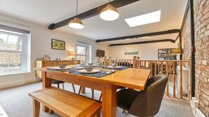 A dining area with a wooden table, benches, and hanging pendant lights. - Host & Stay | The Burrow (Alnwick)