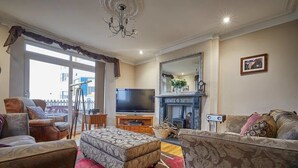 A living room with a television, sofa, ottoman, and fireplace. - Host & Stay | The View Old Coastguard Cottage (North Shields)